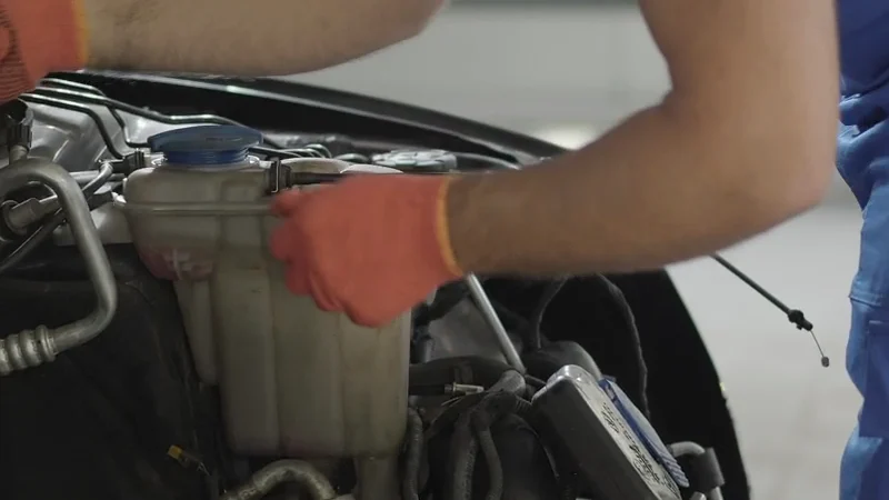 Illustration : les mains d’un mécanicien travaillent avec un outil dans un compartiment moteur.